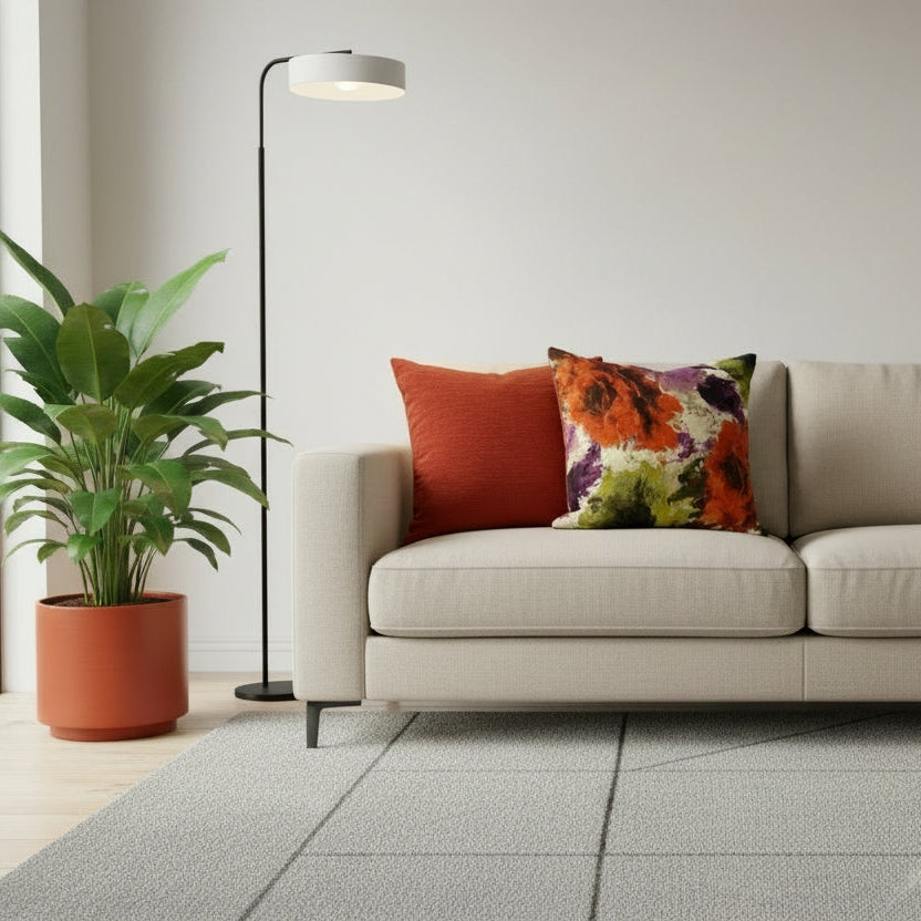Two cushions, one rust orange and one with floral design, on a neutral sofa with a neutral background