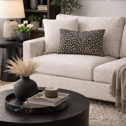 Living room with a beige sofa, leopard print pillow, and decorative items.