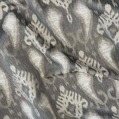 A close-up of draped fabric with an ikat-style pattern in grey, taupe and off-white.