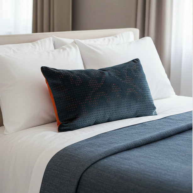 Patterned navy and orange lumbar cushion in a bedroom setting 