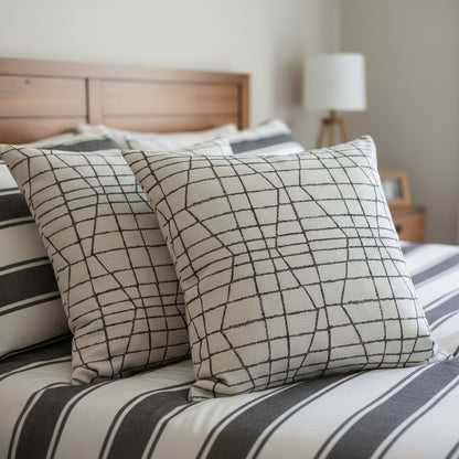 Decorative cushions with a geometric pattern on a bed in a bedroom setting.