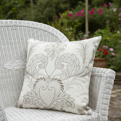 Decorative cushion with intricate damask pattern sitting on a white rattan chair  