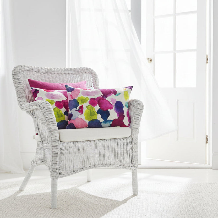 Wicker chair with colourful cushions in a white room, sitting on a white wicker chair 