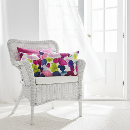 Wicker chair with colourful cushions in a white room, sitting on a white wicker chair 