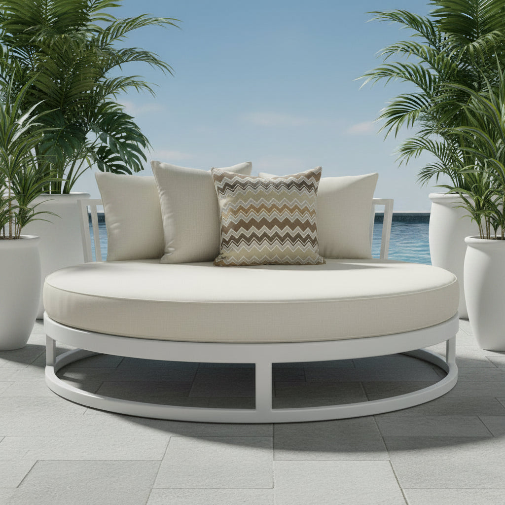 Two outdoor cushions, one plain and one with a zigzag pattern, on a outdoor daybed with white planter pots and lush greenery.