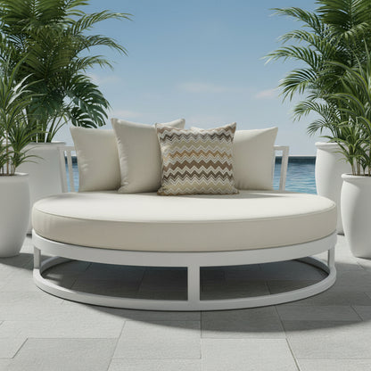 Two outdoor cushions, one plain and one with a zigzag pattern, on a outdoor daybed with white planter pots and lush greenery.
