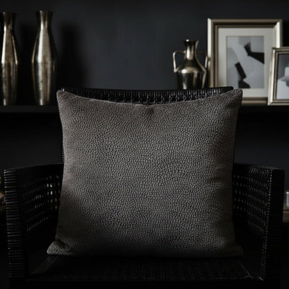 Textured cushion a dark wicker chair with decorative vases and framed pictures in the background.
