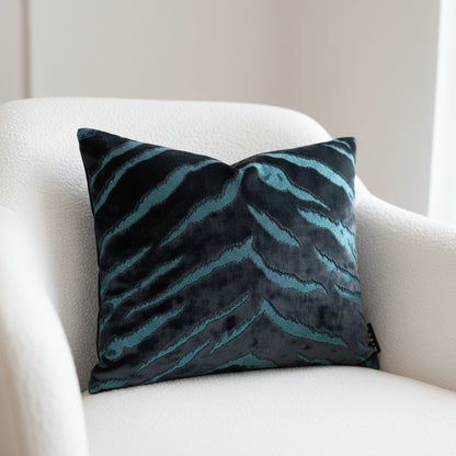Decorative cushion with sapphire and turquoise bengal tiger pattern on a white boucle chair 