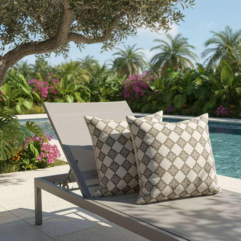 Outdoor lounger with patterned cushions by a poolside with greenery