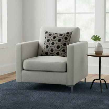 Gray armchair with a patterned pillow in a room with a small table and plant.