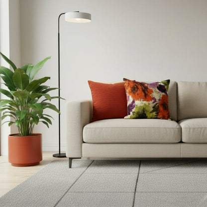 Two cushions, one rust orange and one with floral design, on a neutral sofa with a neutral background