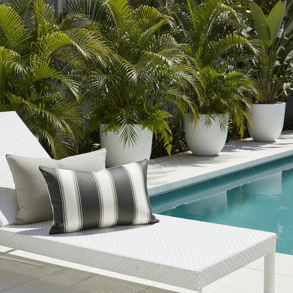 White sun lounger with a striped and plain cushion by a poolside with potted greenery