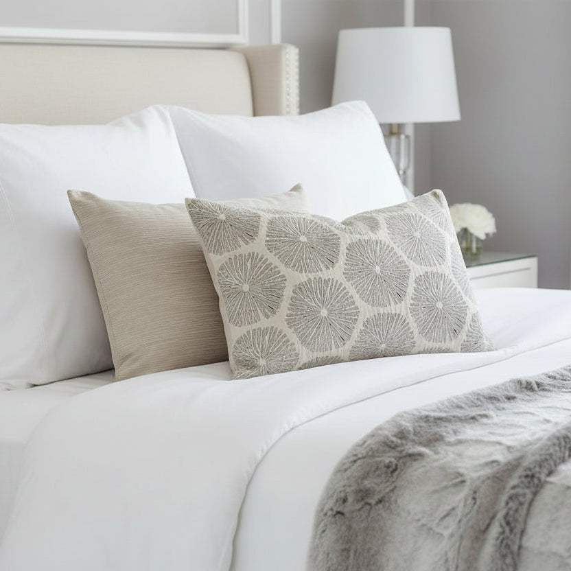 Neatly made bed with decorative cushions and a lamp in the background