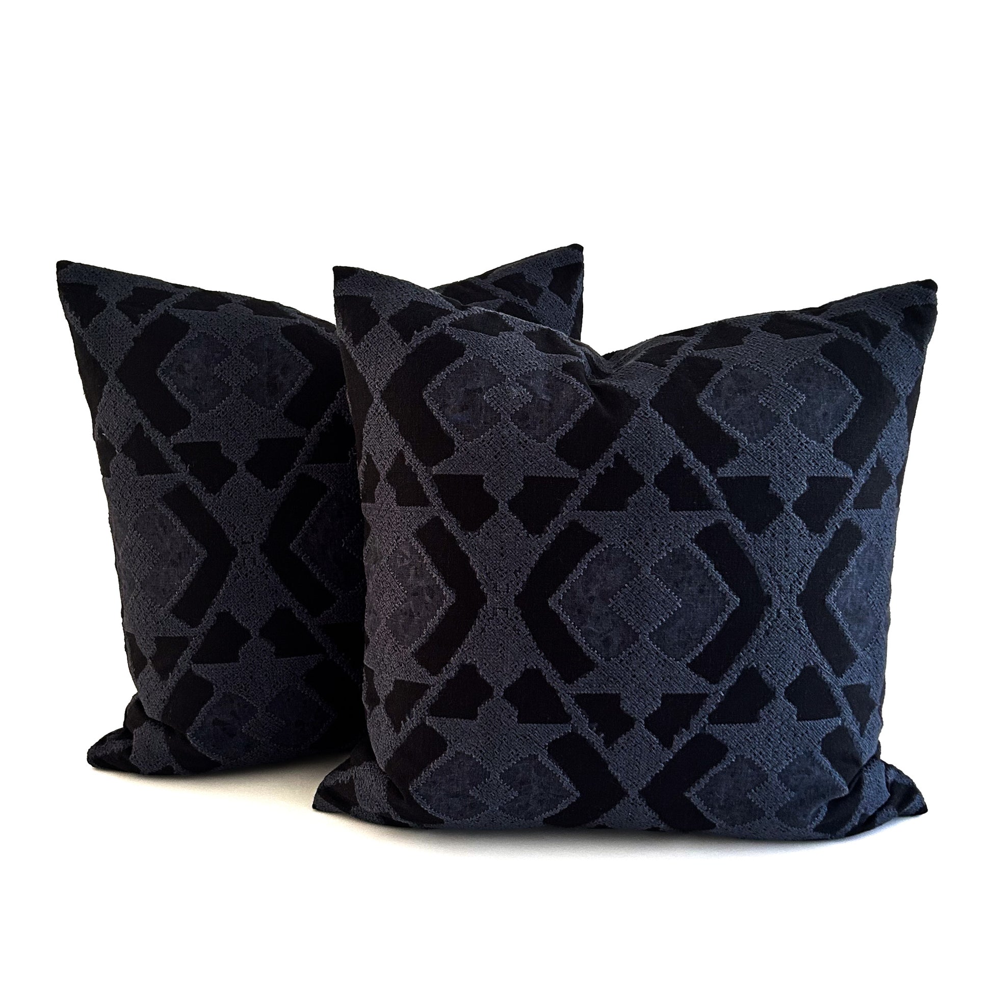 Two dark navy patterned cushions on a white background