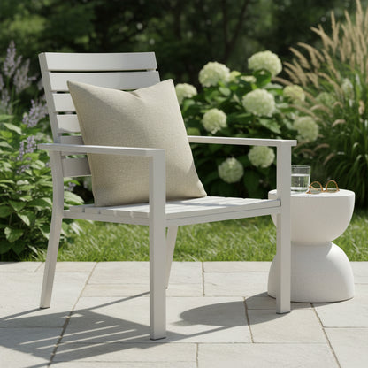 Dove coloured outdoor cushion sitting on a white wooden chair in an outdoor setting.